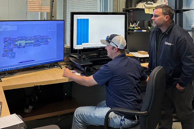 Untitled design - 1 Brian Kelley, building systems tech team leader with Facilities Building Maintenance and Ops, and Joe Collins, systems engineer examine the layout of UD's residence hall HVAC systems on a computer.