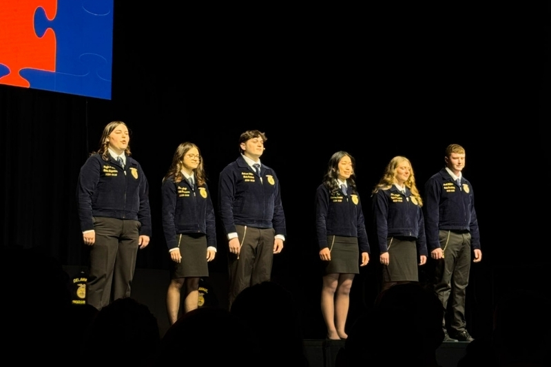 Students stand in a line on stage.