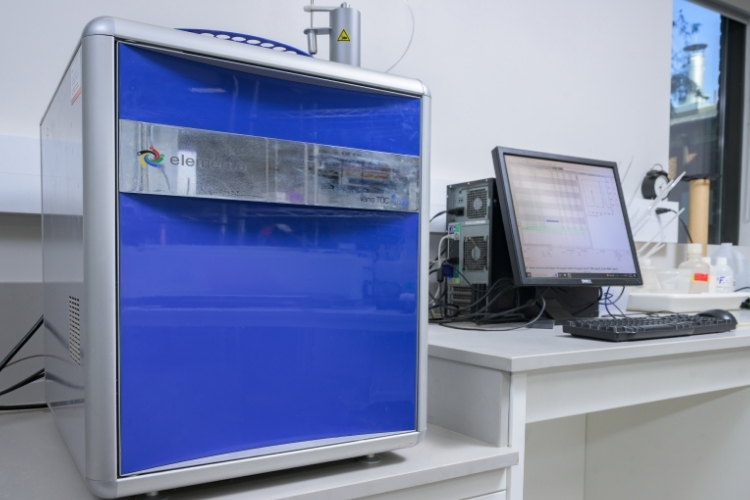 A medium-sized blue Elementar TOC Analyzer next to a computer in a lab.