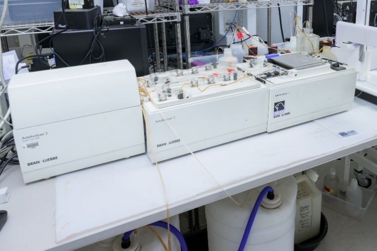 Three medium-sized machines that make up the Auto Analyzer sitting in a lab.