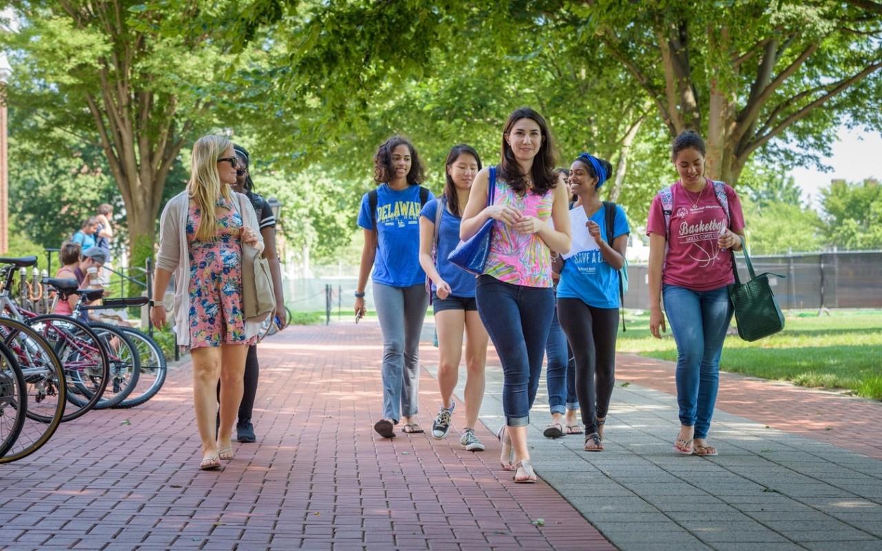 A group of University of Delaware students walk along a brick pathway on The Green, exploring campus.
