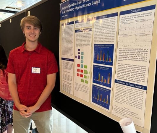  Jeffrey Woulfe was a 2023 summer research fellow standing in front of a poster