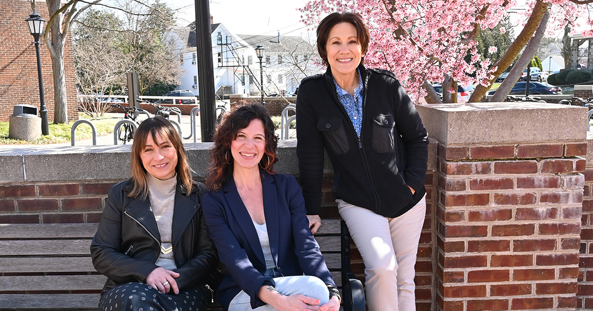 Asia Friedman, Ann Bell, Tammy Anderson appointed editors of Sociological Forum A group of three female University of Delaware professors on the UD campus in front of a red brick wall and a blooming pink cherry tree.