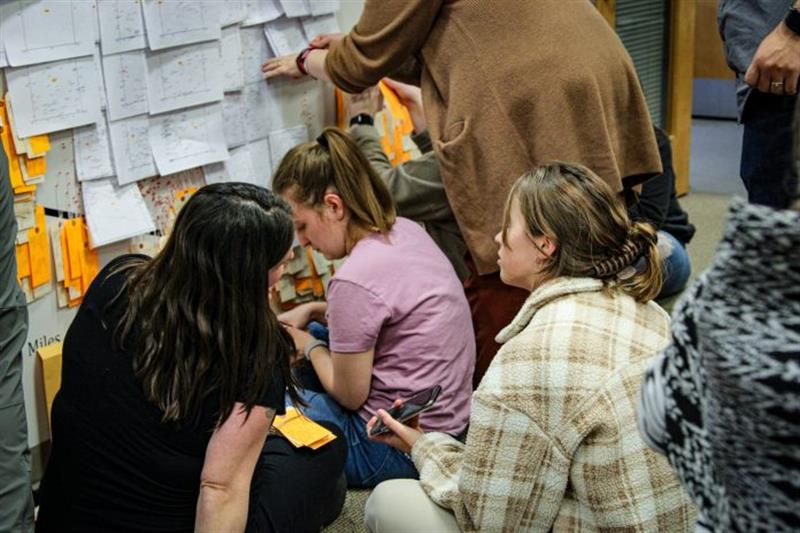 People in a classroom in with sticky notes on wall