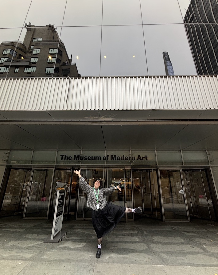 Emily poses outside of the Museum of Modern Art entrance. student posing in front of Museum of Modern Art