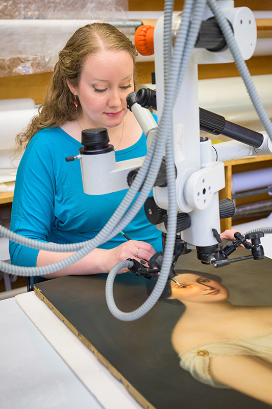 Elizabeth using a microscope to examine the paint on the figure’s face. 