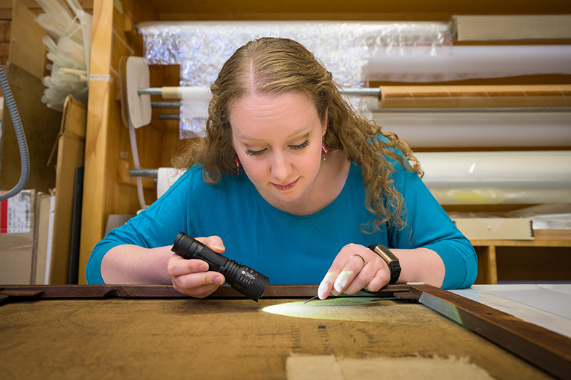 Elizabeth Glander using a raking light across a painting