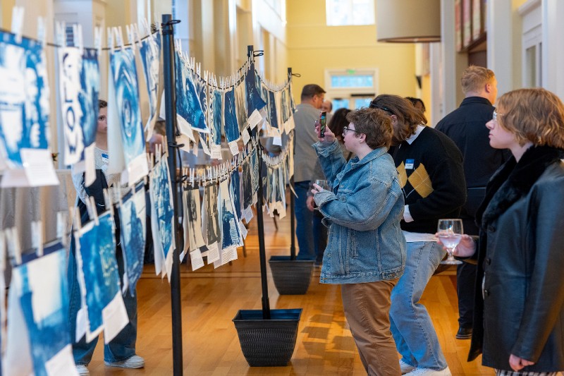 Reception guests examine prints on display in the Gore Recital Hall lobby