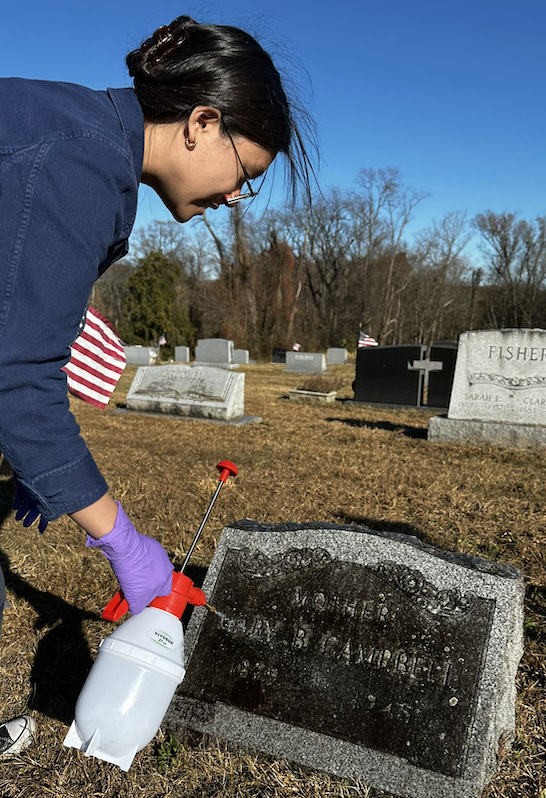 Student cleaning off gravestone