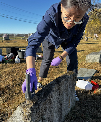 Student scrubbing gravestone