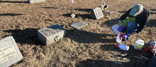 Person cleaning off gravestone