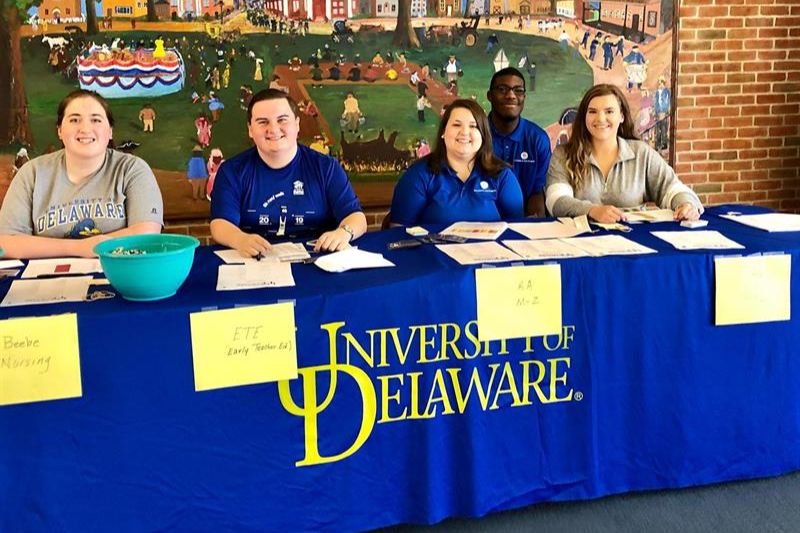 Five people sittig behind a table that says University of Delaware for a welcome event