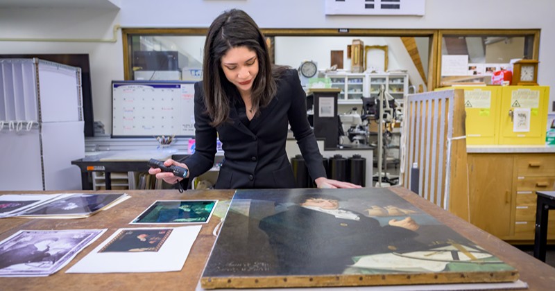 Winterthur/University of Delaware Program in Art Conservation Fellow Zoe Avery examining the portrait.