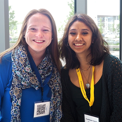 Two smiling college students wearing lanyards with name badges.