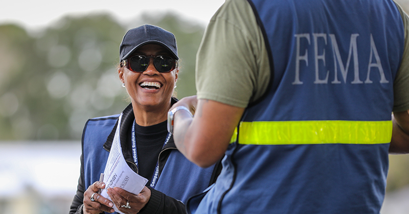 Two employees wearing FEMA uniforms working on site.