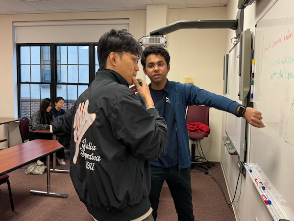 Two students looking at a white board