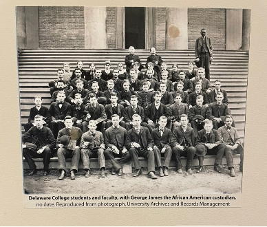 Historic black and white image of male college students gathered for a group photo on the steps of an academic hall at the University of Delaware.