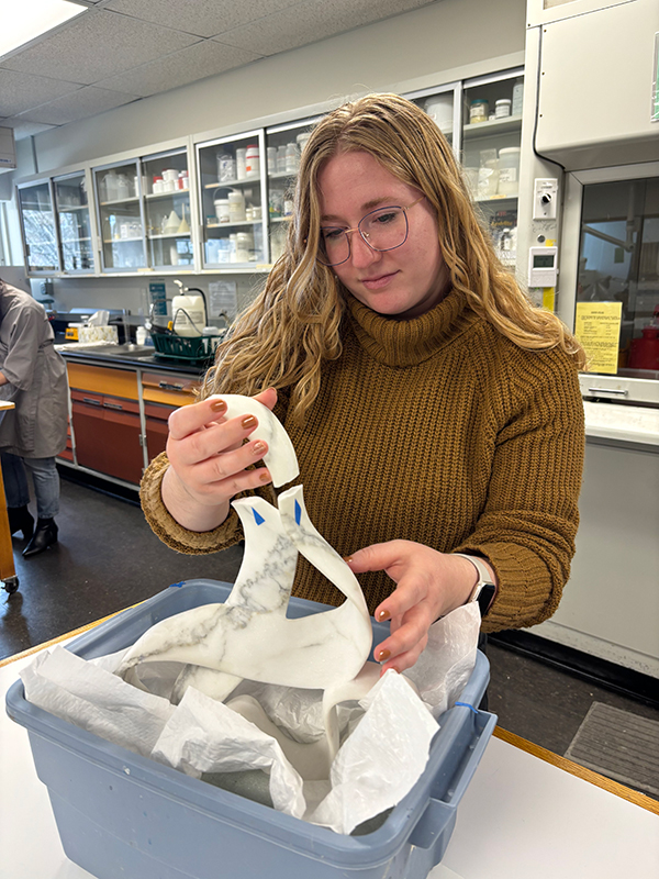 Student in a laboratory working on a fractured marble sculpture.