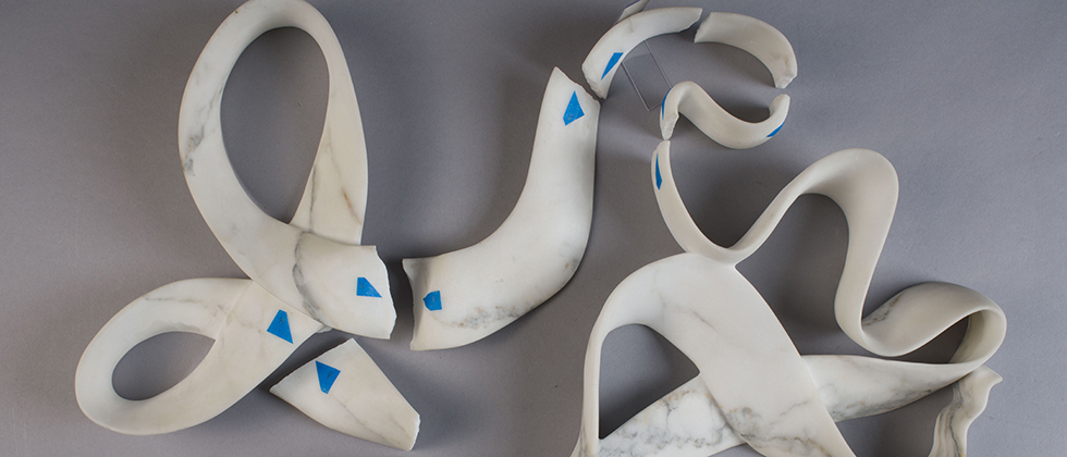 Damages marble ribbon sculpture with blue labels marking the fractured pieces