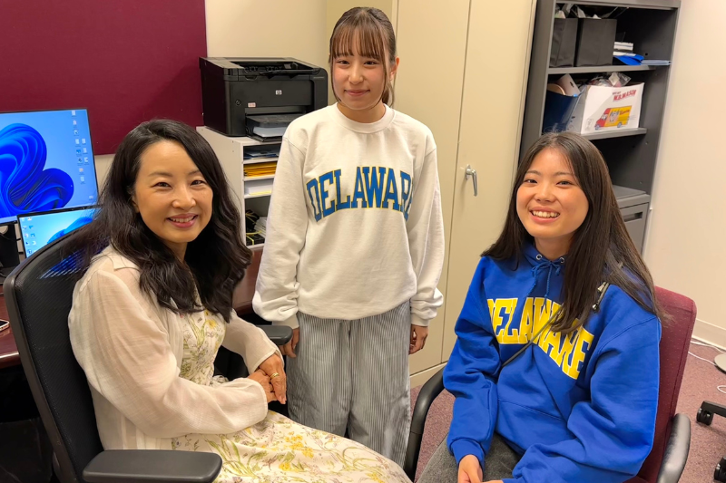 Three female international students wearing University of Delaware gear