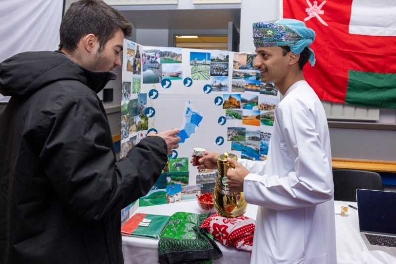 Two international male students at an event with a poster board