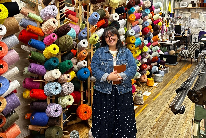 A woman posing with yarn in the background