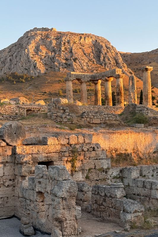 The North Market and Temple of Apollo in the archeological site of Ancient Corinth, with Acrocorinth visible on the top of the hill. The North Market and Temple of Apollo in the archeological site of Ancient Corinth, with Acrocorinth visible on the top of the hill.