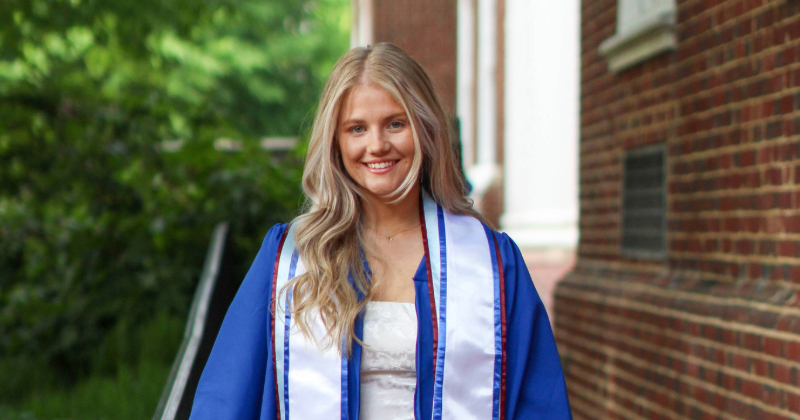 A University of Delaware college graduate dressed in graduation regalia.