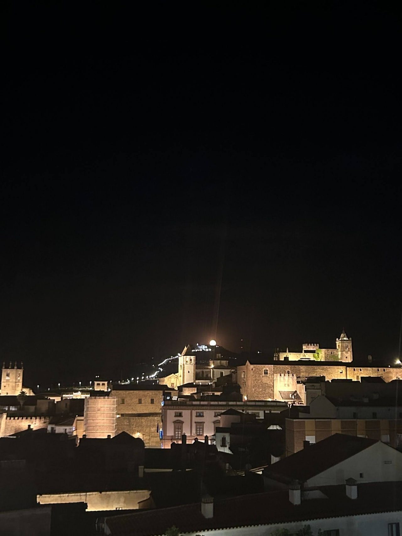 A view of the mountain with a nearly full moon from the top of a rooftop restaurant.