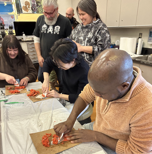 WUDPAC Class of 2026 Fellow Caitlyn Fong and NMAI staff processing salmon fish skins under the guidance of Stevi Angasan