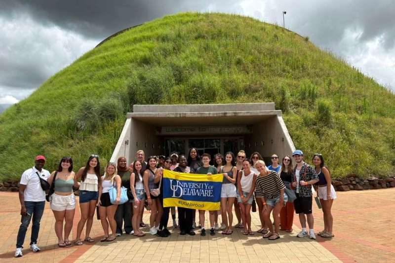 A group of smiling students holding a UD banner gather for a group photo in South Africa.