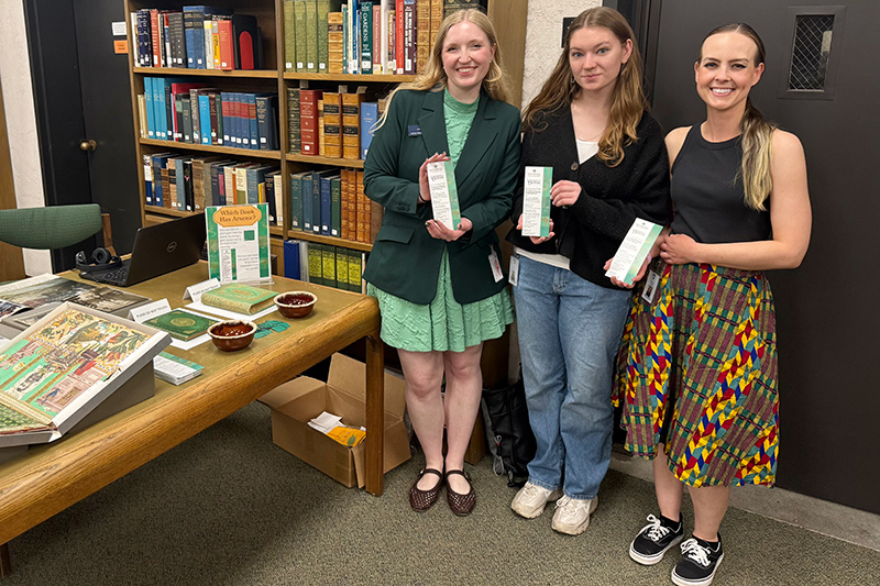 Ashley Vernon with Poison Book Project Team members Caitlyn Winter and Amelia Oakes holding Poison Bookmarks