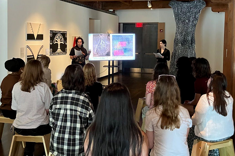 Art history students sit inside an art gallery during a slide presentation delivered by two students 