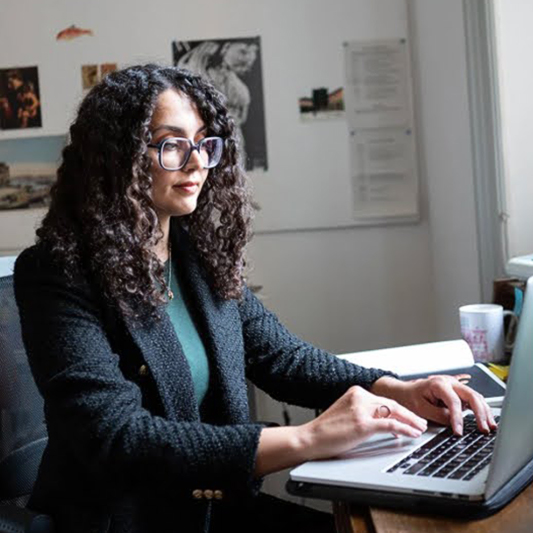 A woman in an office types on her laptop.