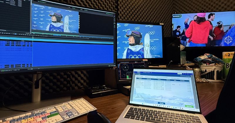 A laptop on a desk and three monitors with images of Olympic skiers.