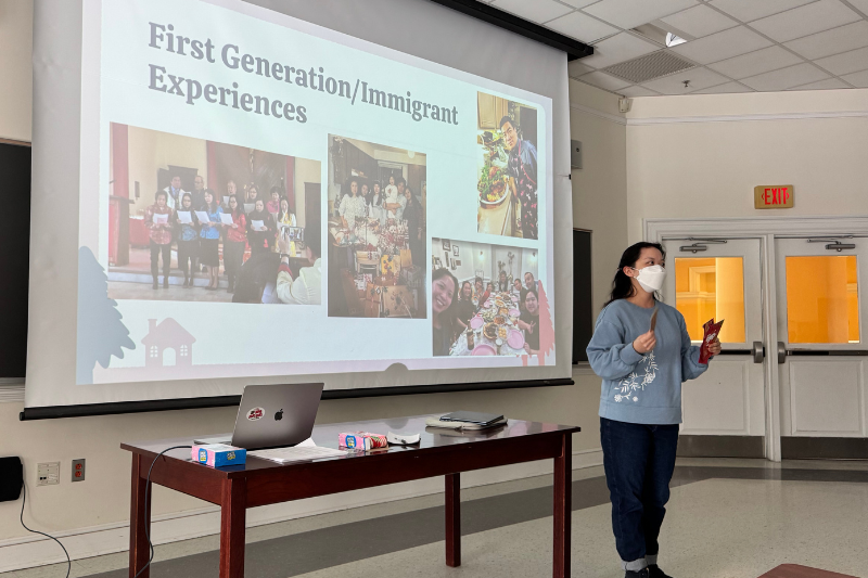 Man shares about the experience of first generation Americans in front of a presentation.