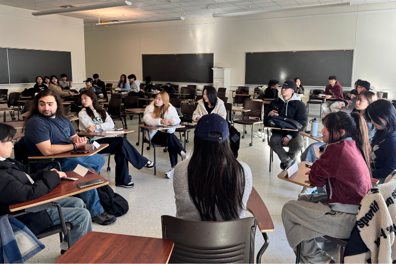 ELI Korean students sit in a circle to talk with UD student, Ata Kitapci, during the Cross-Cultural Discussions course.