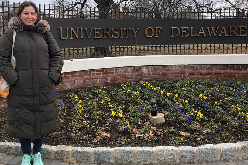 Beyza Saraç ELI student standing in front of University of Delaware signage