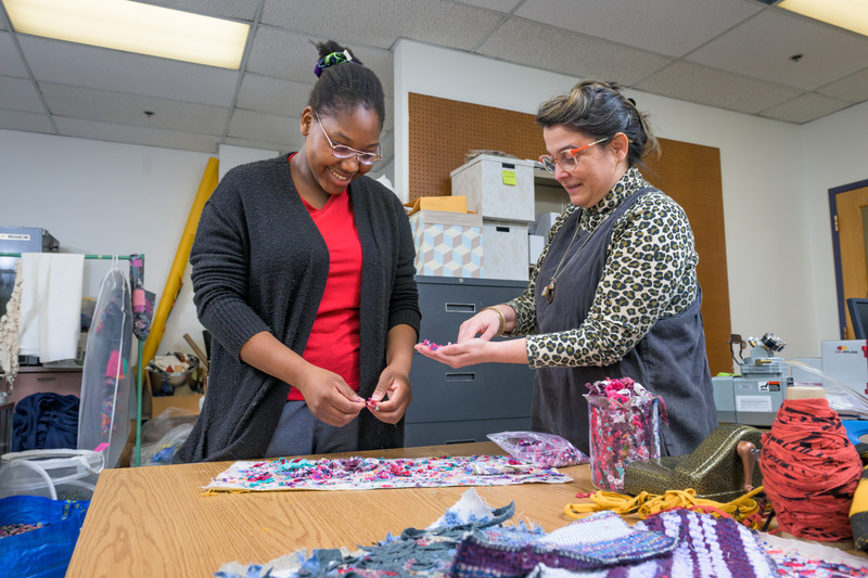 A college professor and a student work on textiles in a laboratory