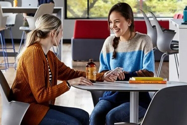 Two college students sitting and talking at a table.