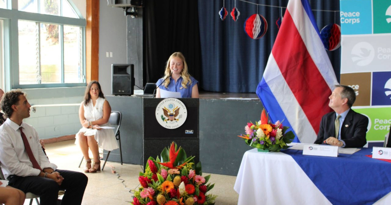 A college student behind a podium with a microphone delivers remarks to an audience.