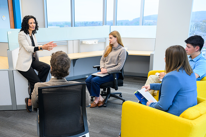 A clinical supervisor addresses four student clinicians in an office.