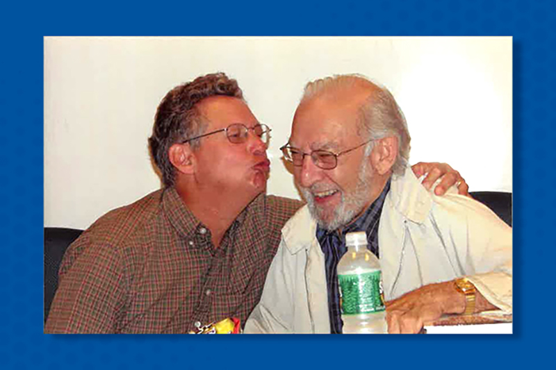 Image on blue background of two men laughing together
