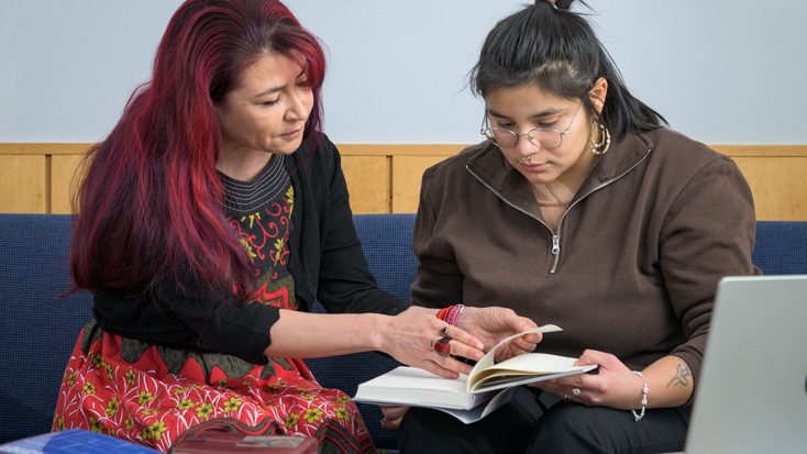 Faculty and student looking at a book