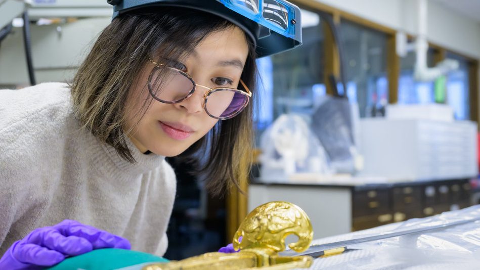 Student with art conservation tools inspecting old art