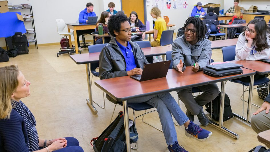 Faculty and students with laptops in a classroom setting