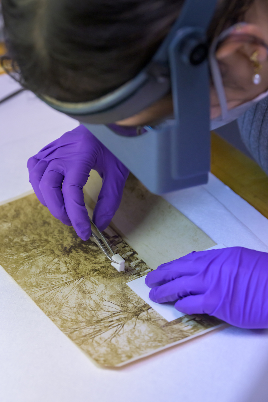  a silver gelatin photograph is being gently surface cleaned with a cosmetic sponge to removed embedded dirt and grime.