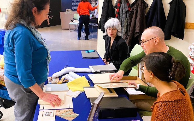 4 people at a blue table with papers