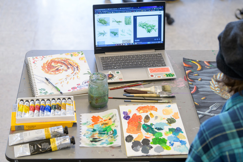 Art tools and eqipment on a table with an open laptop
