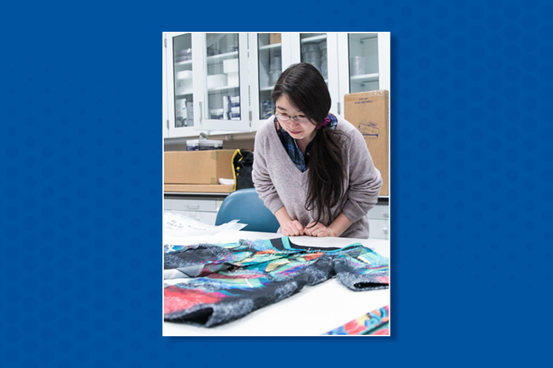 You Jin Choi inspects a Korean textile on a table.